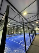 Binnenpadelbaancomplex met blauwe hardcourts, zwarte netconstructies en LED-verlichting