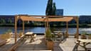 Waterfront padel club met houten pergola's, zitplaatsen en bar aan rivier