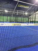 Padelclub Rotterdam indoorbaan met blauw hardcourt en net, professionele verlichting