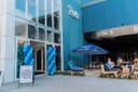 Padel club ingang met blauwe ballonnen decoratie en terras met parasol