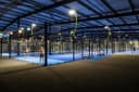 Moderne overdekte padelbaan met blauwe harde ondergrond en professionele verlichting