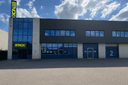 BTNCK padel club gebouw met blauwe deuren, grote ramen en gele signage tegen blauwe lucht.