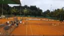 Outdoor padelbanen met oranje ondergrond en groen windscherm op tennisclub
