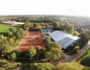 Luchtfoto van padelbanen met rode ondergrond en overdekt plein, omgeven door groen