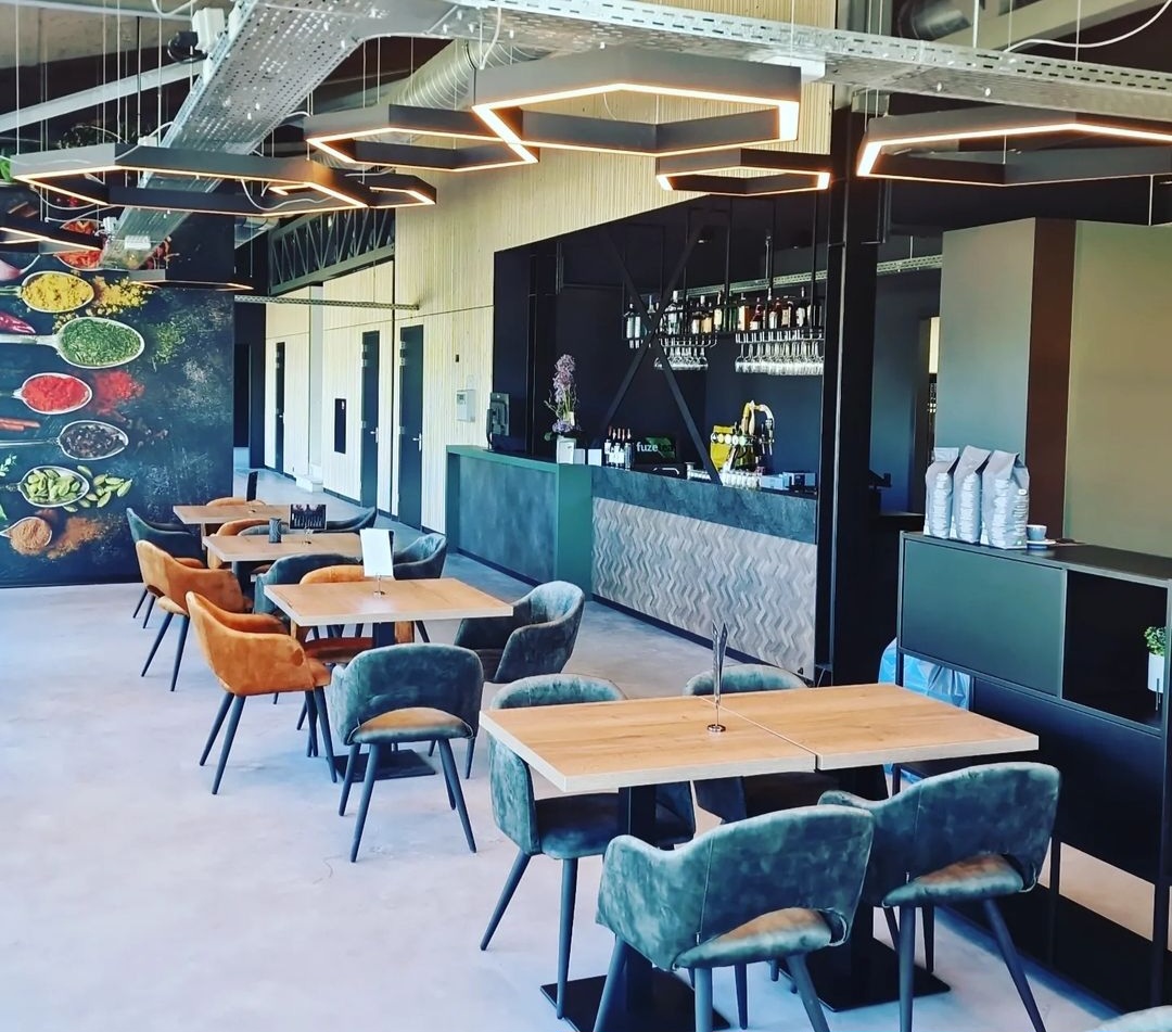 Modern padel club interieur met bar, groene stoelen en houten tafels onder led-verlichting