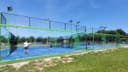 Moderne outdoor padelclub met blauwe kunststofbanen, groene frames en floodlights