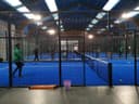 Indoor padelclub met blauwe kunstofgrass courts, zwarte netten en LED-verlichting