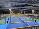 Moderne indoor padelclub met meerdere blauwe courts, LED-verlichting en glazen wanden