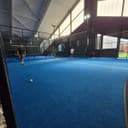 Binnen padelclub met blauwe kunststof banen, netwerking en moderne faciliteiten