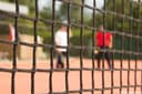 Padelnetje met onscherpe spelers en rode shirts op achtergrond