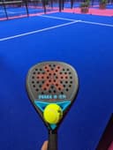 Osaka padelracket met gele bal op blauw quickpadel veld met omheining